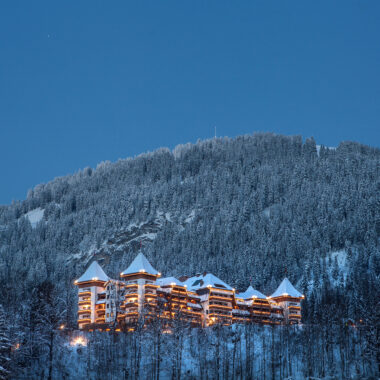 The Alpina hotel in Gstaad, Switzerland, lit up against a snowy mountain at night