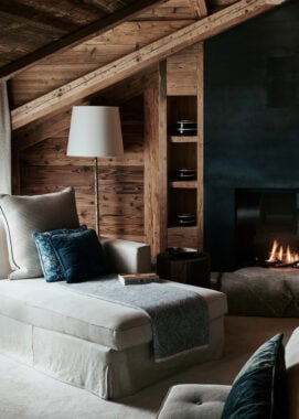 A sofa by a fire in The Alpina in Gstaad, Switzerland