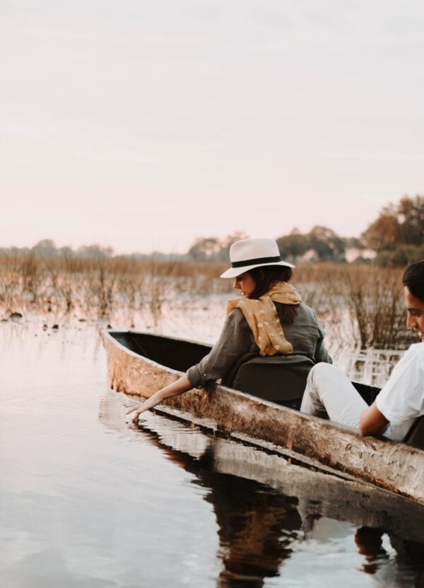 A woman dipping her hand into calm water from a canoe