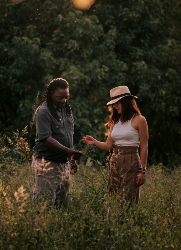 A man showing a woman in a hat a plant on a nature walk