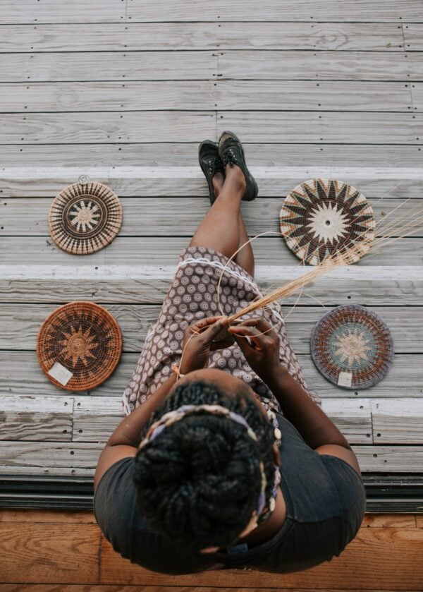 Aerial shot of a woman weaving traditional mats with grass reeds