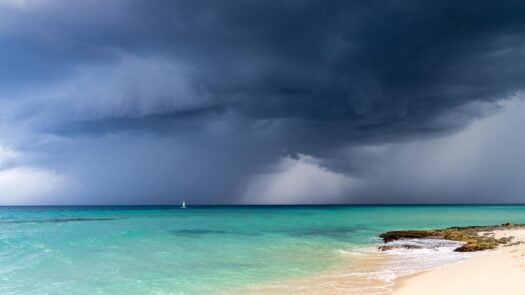 Dramatic view of dark grey storm clouds against the turquoise blue water of the Caribbean sea