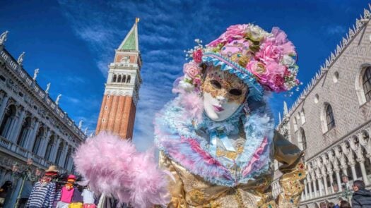 Carnival mask against bell tower on San Marco square in Venice