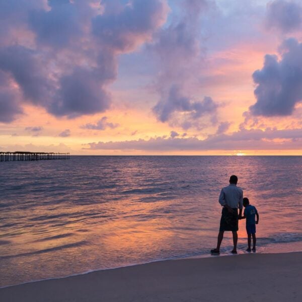 Father and son at dramatic sunset by the sea in Alleppey Alappuzha Beach Kerala India