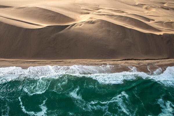 Aerial view of Skeleton coast sand dunes meeting the waves of Atlantic ocean. Skeleton coast, Namibia.