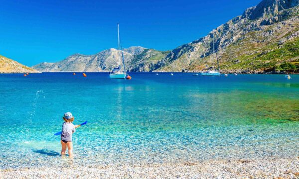 Amazing sea bay on Greek Island with a small boy at play on the seashore, Greece