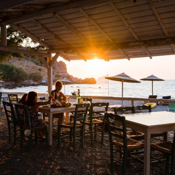 Family enjoying dinner in a restaurant on the beach at sunset.