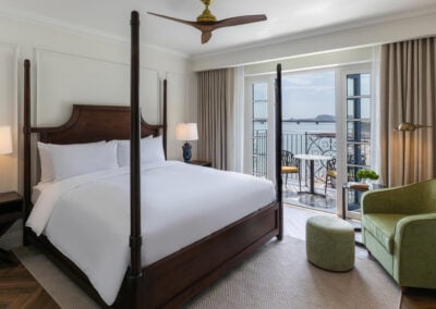 Interior bedroom with four poster bed, green arm chair and balcony