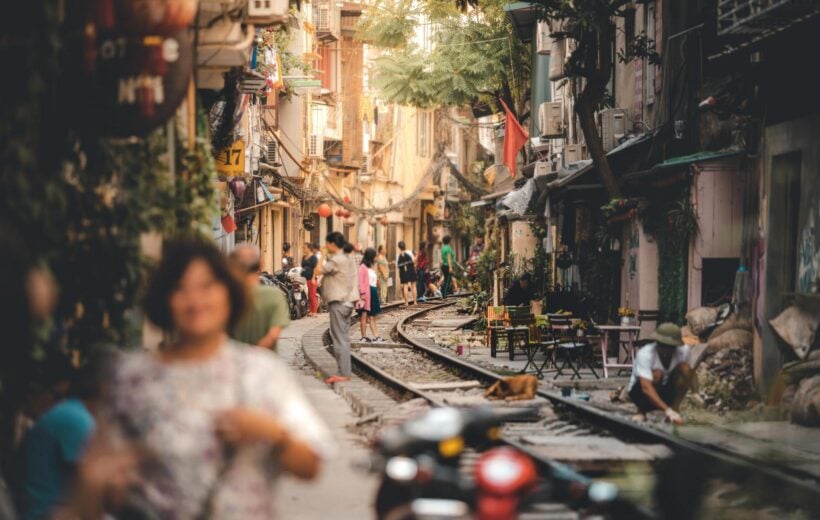 Tourists walk down the tracks of the famous Train Street in Hanoi, Capital of Vietnam