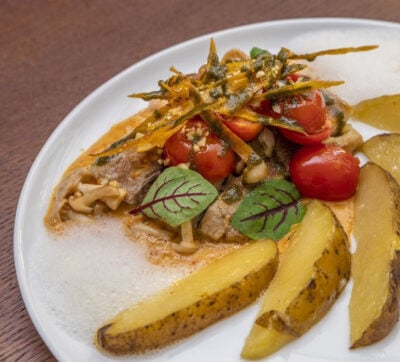 Close up of plate of food with potato wedges, tomatoes, mushrooms and steak in sauce