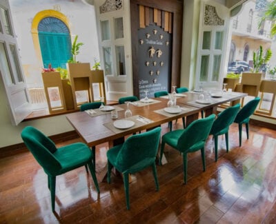 Dining area at hotel with long wooden tableaand plush green chairs