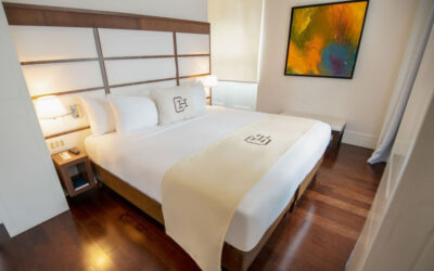 Bedroom with large white bed and shiny wooden floor