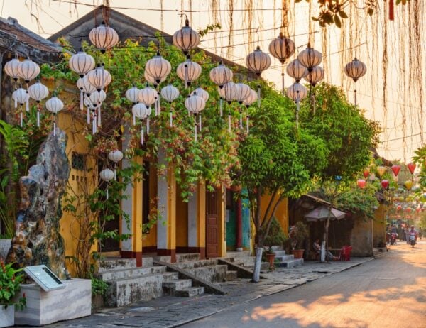 Awesome view of cozy street decorated with colorful silk lanterns at sunrise. Scenic traditional old yellow houses of Hoi An Ancient Town, Vietnam. Hoian is a popular tourist destination of Asia.