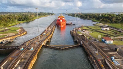 A view of an orange ship making its way down the Panama Canal