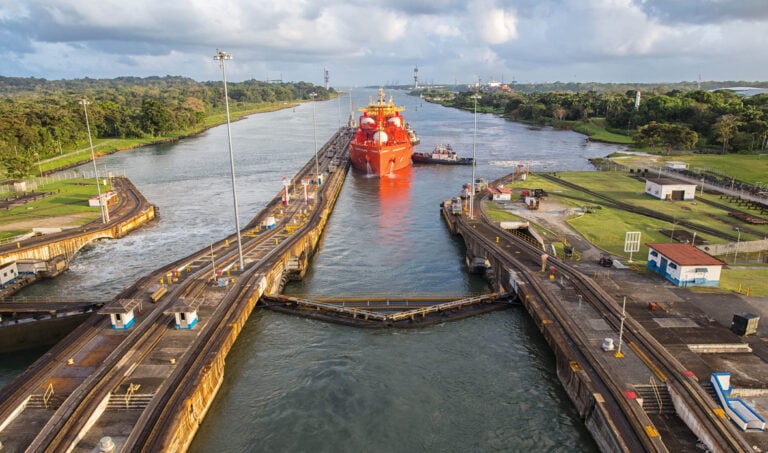 A view of an orange ship making its way down the Panama Canal