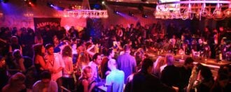 A nightclub in Thessaloniki, filled with people eating at tables, drinking, and dancing