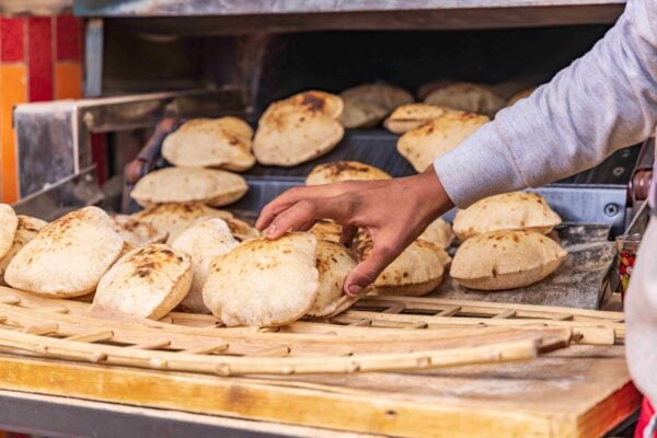 Baker making fresh pita bread, known as aish, in Manshiyat Naser, Garbage City, Cairo.