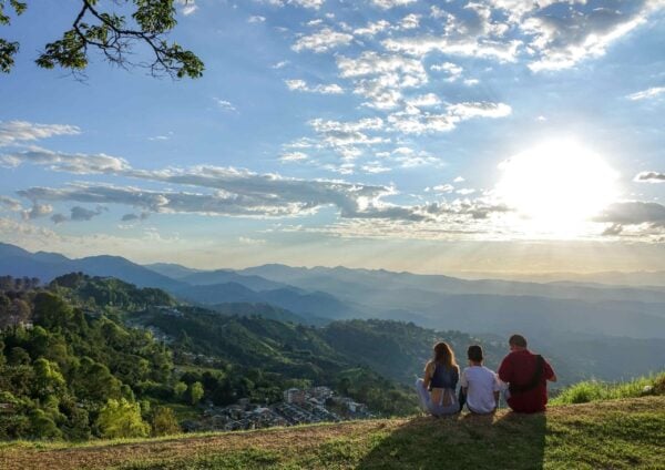 Family enjoying a sunset view over rolling hills and distant mountains in Manizales, Colombia