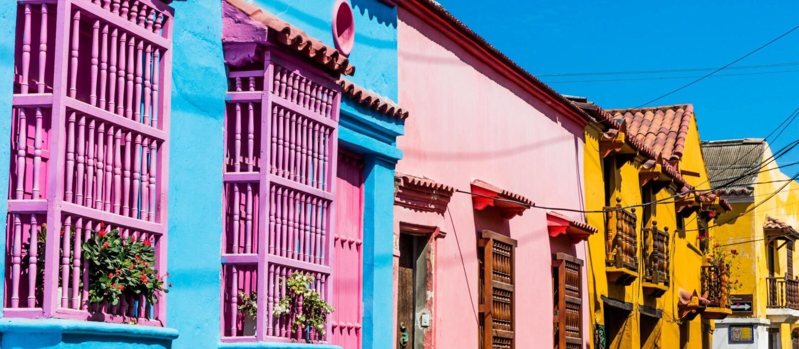 Rainbow coloured buildings with bright window shutters in a street in Cartagena Colombia