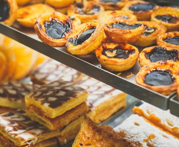 Traditional Portuguese egg tart pasty cakes, dessert Pasteis de nata with different portuguese pastry on the cafe store window, pastel de nata