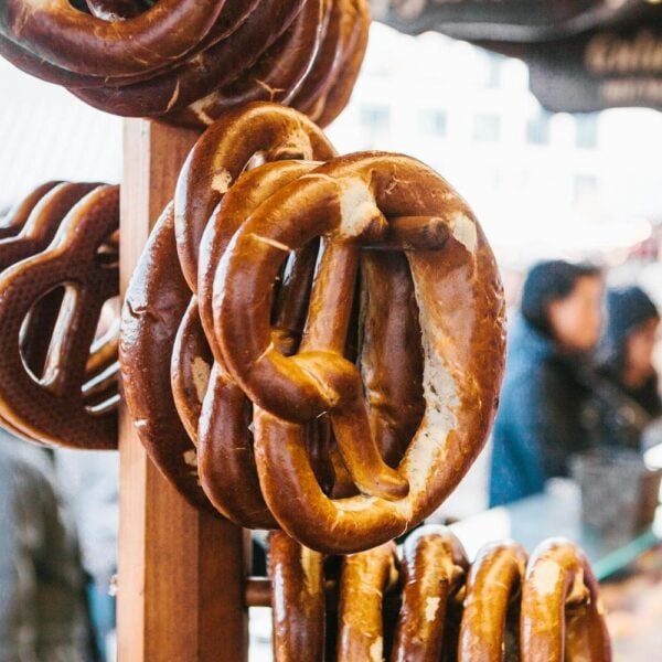 Traditional pretzels called Brezel hang on the stand against the background of a blurred street market and people on holiday.