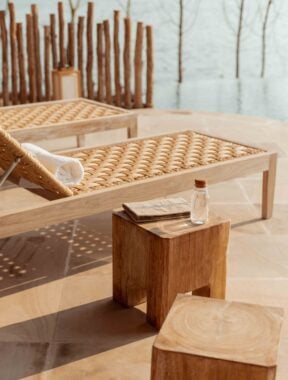 An outdoor seating area with wooden sun loungers and a small cube shaped table