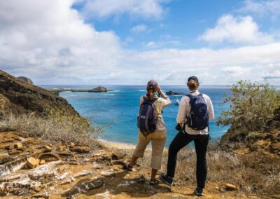 Two people standing on a rocky hillside looking over the sea