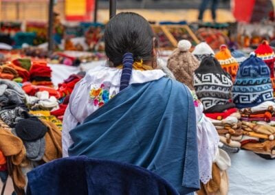 Indigenous women in traditional clothing and hairstyle by her market stall on the sunday art and craft market of Otavalo, North of Quito, Ecuador.