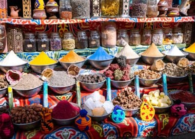 Bowls of colourful powdered spices and whole spices on a brightly patterned table cloth