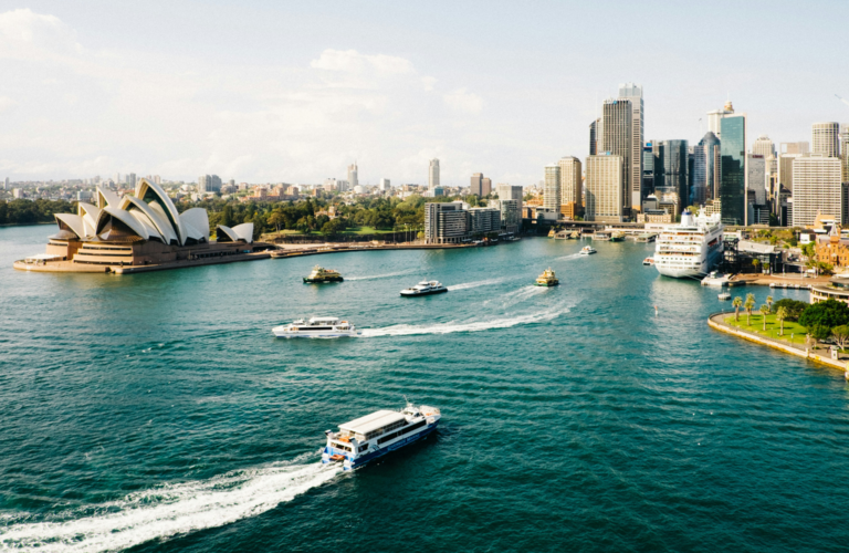 Sydney Harbour and city skyline, with ferries and small boats leaving the quayside, and the Opera House visible