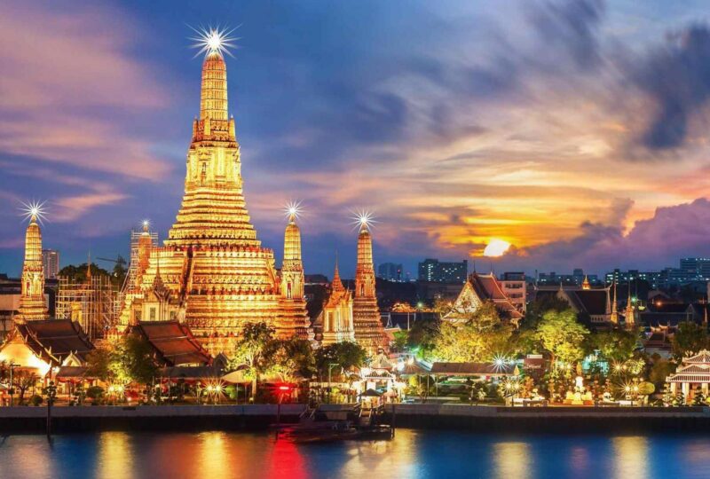 A view of Wat Arun temple along the Chao Phraya river at night in Bangkok