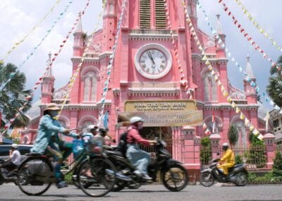 Scooters going past a pink catholic church in Ho Chi Minh City, Vietnam