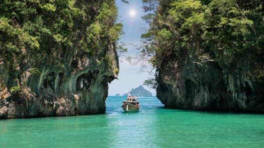 A boat sailing between two walls of rock in Phuket, Thailand