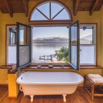 A bathroom with open windows overlooking the lake at Las Balsas hotel in Argentina