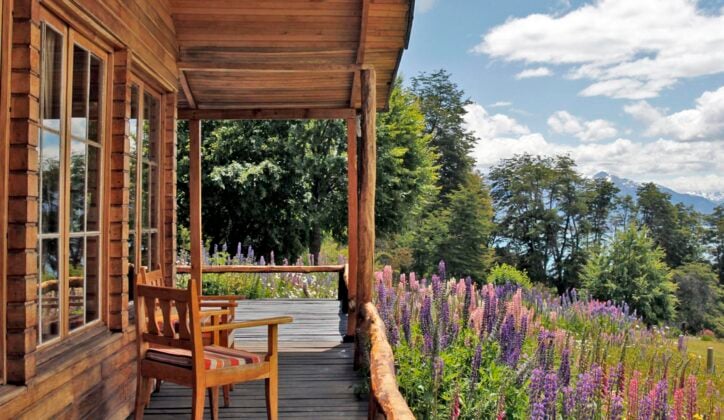 An outdoor terrace overlooking flowers, fields and mountains at Mallin Colorado, Chile