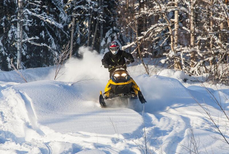 A person riding a snowmobile through a forest