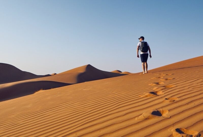 A man hiking through sand dunes in the Omani desert