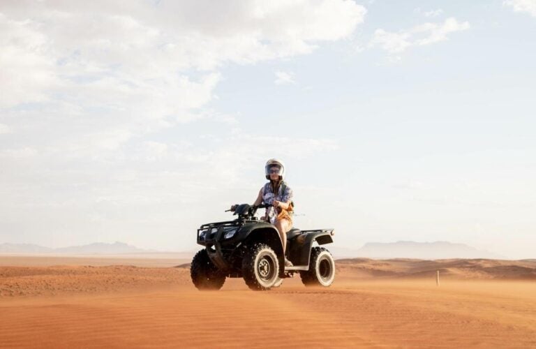 A person riding a quadbike through the sand dunes at Sossusvlei, Namibia