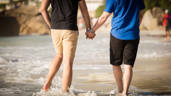 Close up image of a gay male couple holding hands on the beach in cape town south africa