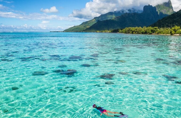 Luxury travel vacation tourist woman snorkeling in Tahiti ocean, Moorea island, French Polynesia.