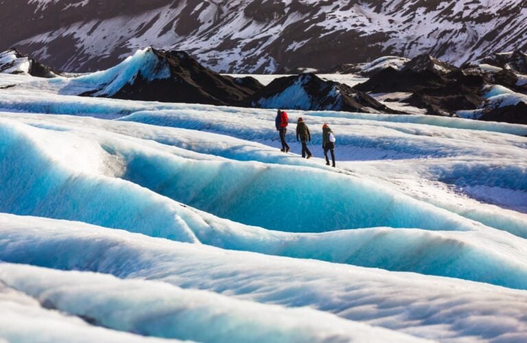 Private guide and couple of hiker walking on glacier at Solheimajokull, Iceland