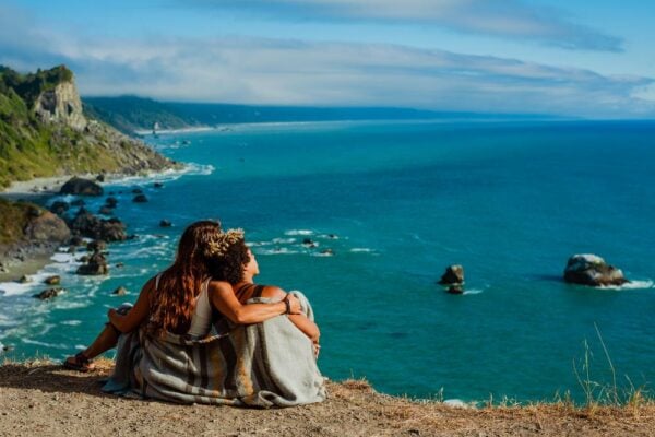 Couple sitting on the ground overlooking a beautiful coastline