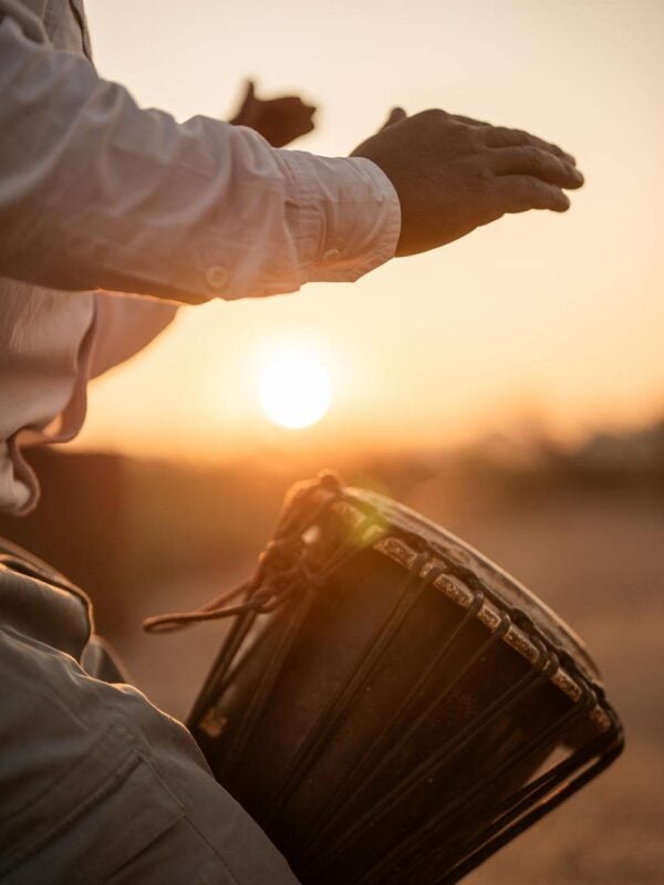 Wilderness Desert Rhino Camp hands seen playing the drums in sunset light