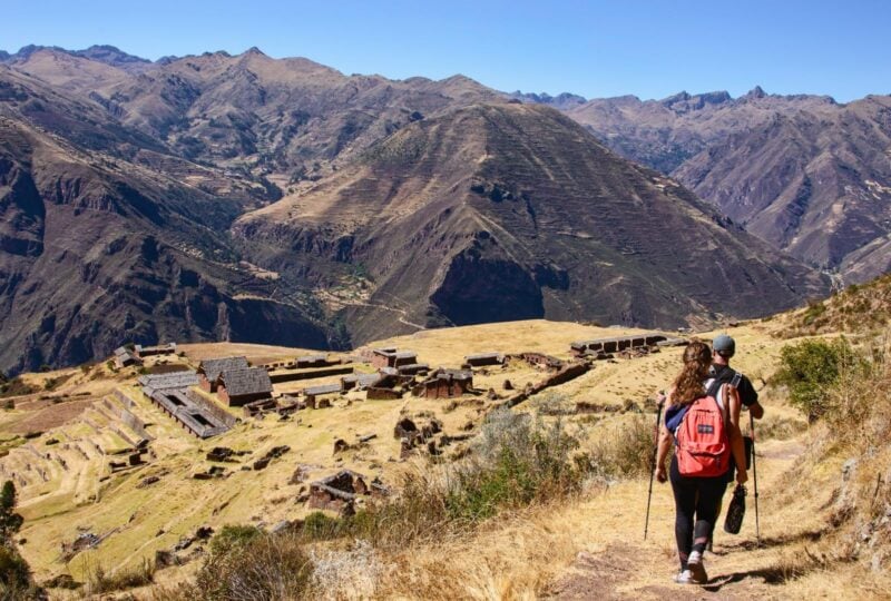 A man and a woman trekking past Incan ruins on the Inca Trail, Peru