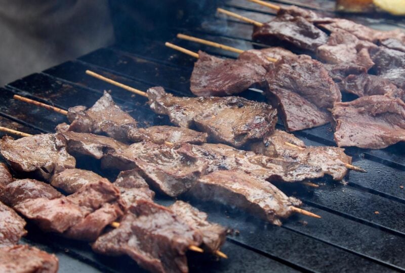 Anticuchos being cooked over a grill in Peru