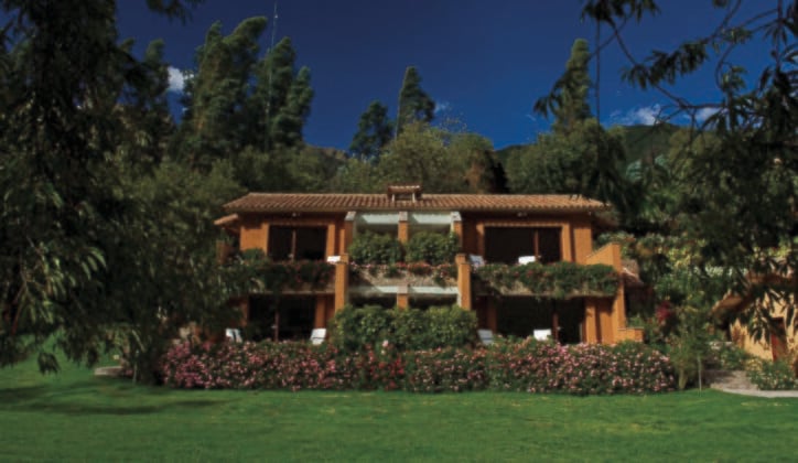 The exterior of Hotel Rio Sagrado surrounded by trees and flowers